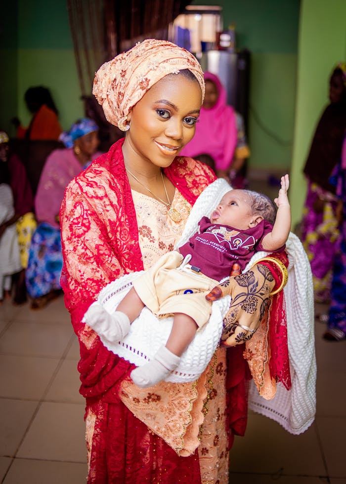 services-03 A joyful mother in colorful traditional attire lovingly holds her baby indoors.