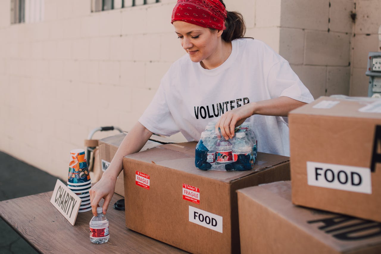 services-04 Woman volunteer sorting food and water for charity distribution at aid center.